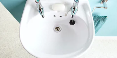 O chiuvetă de baie curată, alături un prosop.  