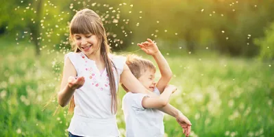 Brat i sestra igraju se na polju maslačaka okruženi peludi