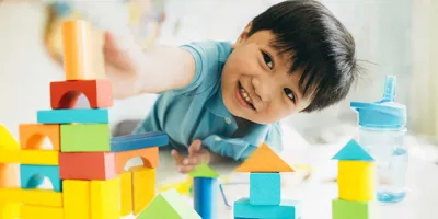 Ένα αγόρι παίζει με πολύχρωμα ξύλινα παιχνίδια