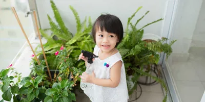 Fată mică îngrijește plante de interior