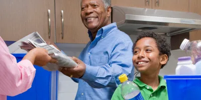 Bunicul îl învață pe băiat să recicleze în bucătărie.