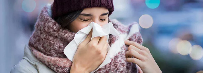 Žena zamotana u glomaznu zimsku odjeću boluje od simptoma sinusitisa i kiše u maramicu na otvorenom