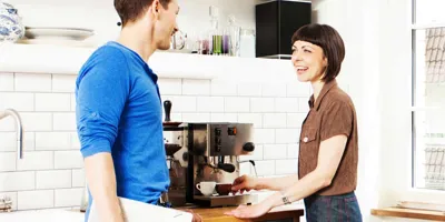 Žena připravující kávu v rozhovoru s mužem v kuchyni