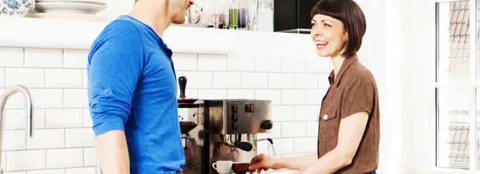 Žena připravující kávu v rozhovoru s mužem v kuchyni