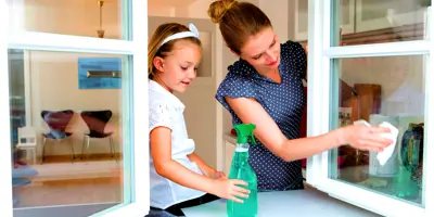 Mutter und Tochter putzen zusammen ein Fenster