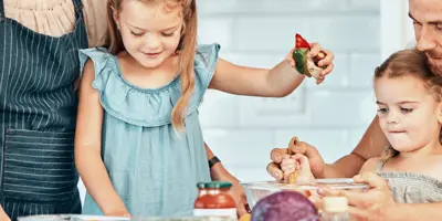 Eine junge Familie mit zwei kleinen Mädchen hat Spaß daran, in der Küche zusammen Essen zuzubereiten.