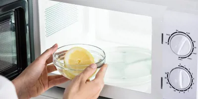 Човек слага тенджера с вода с лимонен в микровълновата фурна