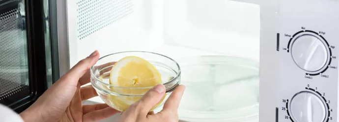 Човек слага тенджера с вода с лимонен в микровълновата фурна