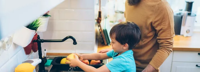 Μια μητέρα βοηθά τα παιδιά της να πλύνουν τα χέρια τους στην κουζίνα