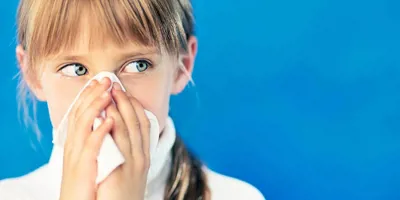Ένα κορίτσι με κρυολόγημα κρατά ένα χαρτομάντιλο μπροστά στη μύτη της