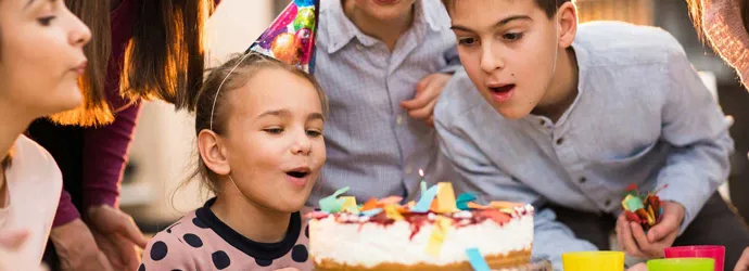 Παιδιά στέκονται γύρω από μια τούρτα σε ένα πάρτι γενεθλίων