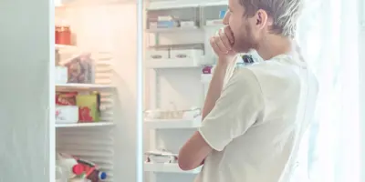 Ein Mann sucht nach Essen in einem Kühlschrank