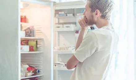 Ein Mann sucht nach Essen in einem Kühlschrank