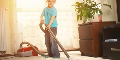 Хлопчик чистить килим пилососом