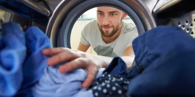 Muž sahá do pračky pro prádlo