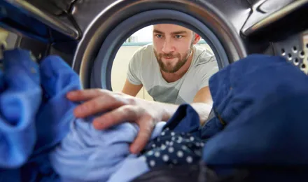 Muž sahá do pračky pro prádlo