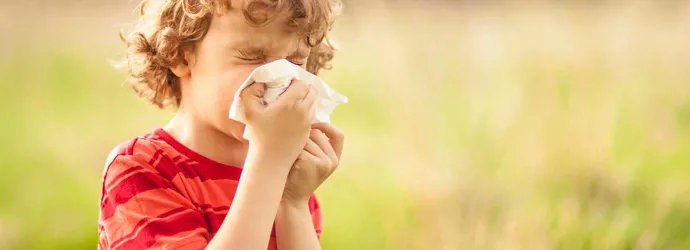 Мальчик с пыльцевой аллергией сморкается снаружи в поле