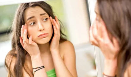 Tinédzser ellenőrzi az allergiától duzzadt szemeit a tükörben
