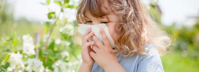 Egy kislány fújja az orrát, hogy enyhítse a pollenallergia tüneteit