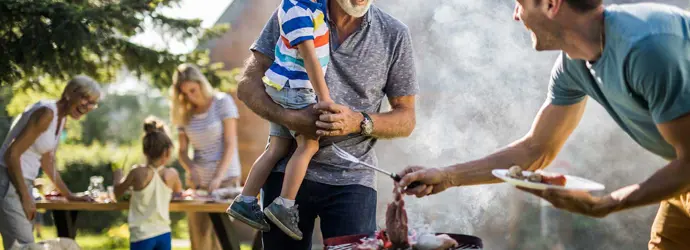 Muž připravuje barbecue na dvorku rodinného domu