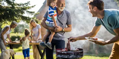 Muž připravuje barbecue na dvorku rodinného domu