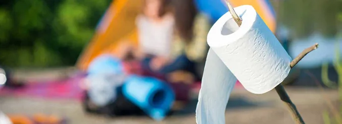 Pisilés a szabadban: WC-papír guriga látható egy boton, a háttérben kültéri játszótér gyerekekkel.  
