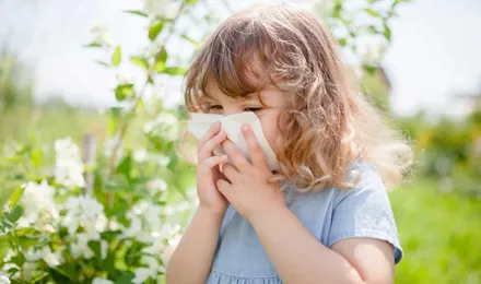 Малко момиче духаше носа си за облекчаване на алергия към цветен прашец