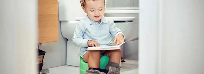 Chlapec na nočníku s knihou na klíně