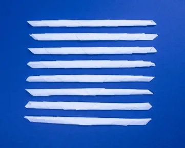 Felcsavart papírzsebkendő csíkok kék asztalon.