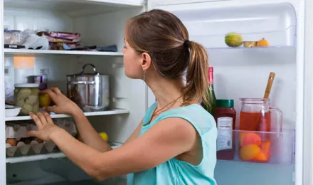 Жінка перевіряє та миє внутрішню сторону холодильника