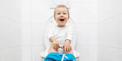Dijete sjedi na WC-u u bijeloj kupaonici