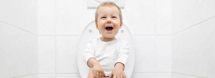 Dijete sjedi na WC-u u bijeloj kupaonici