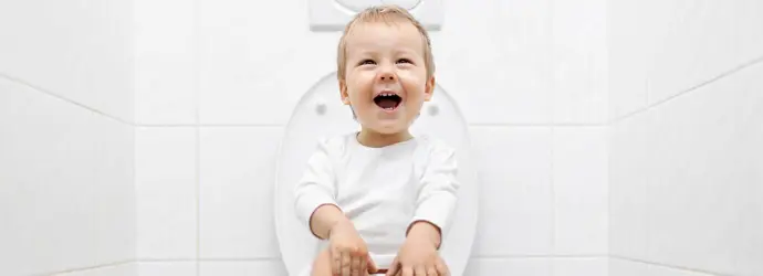 Dijete sjedi na WC-u u bijeloj kupaonici