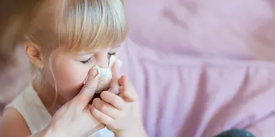 Egy anya segít lányának fújni az orrát papír zsebkendővel