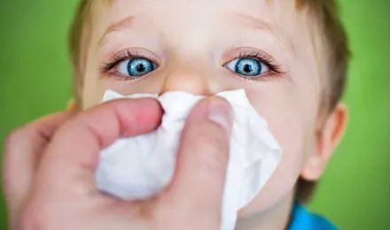 A fiú orrát tisztítják papír zsebkendővel