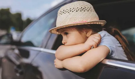 Copil cu greață în mașină purtând o pălărie în timp ce