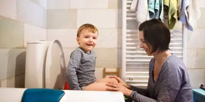 Eine Mutter hilft ihrem Sohn, der im Badezimmer auf einem Töpfchen sitzt