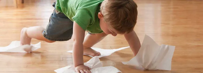 Copil care curăță podeaua cu prosoape de hârtie