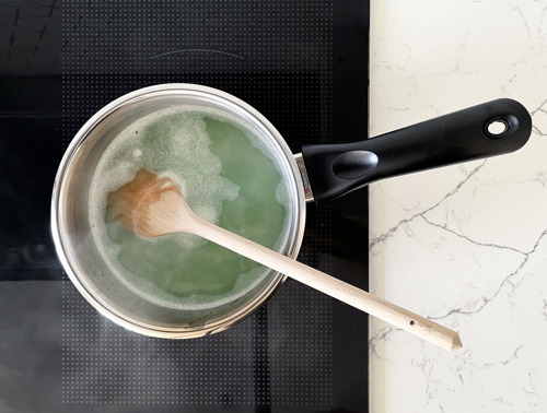 Ein Topf auf einem Ofen mit dem Zitronenreiniger und einem hölzernen Kochlöffel.