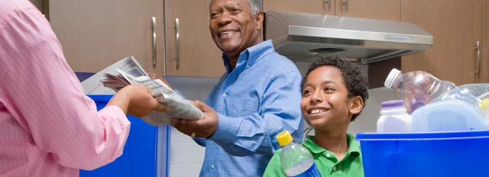Deda uči dečaka reciklaži u kuhinji.