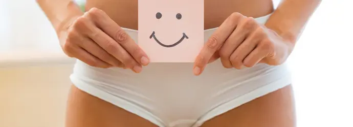 Eine Frau in Unterwäsche hält einen Zettel mit Smiley an ihren Bauch.