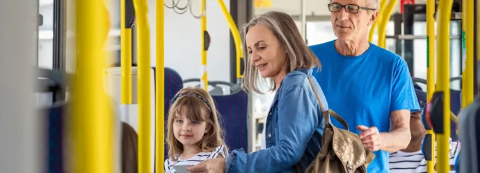 Familie cu copil urcând în autobuz, pe șine galbene.