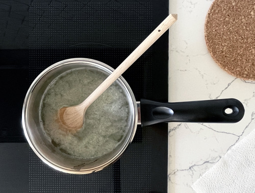 Ein Topf auf einem Ofen mit dem kochenden Zitronenreiniger und einem hölzernen Kochlöffel.