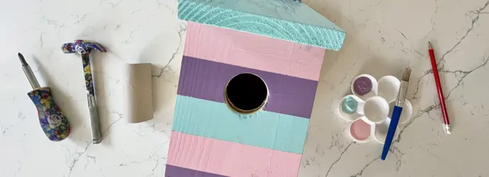 Otec a syn natírají ptačí budku na zahradě