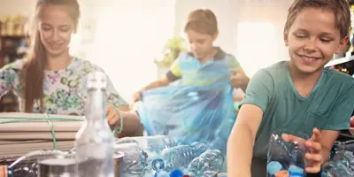 Τα παιδιά ταξινομούν τα πλαστικά μπουκάλια για ανακύκλωση στο σπίτι.