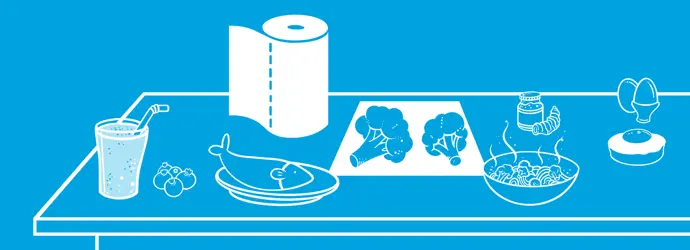 Жінка працює на комп'ютері та їсть салат за столом