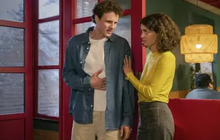 Ein Mann und eine Frau stehen an der Tür eines Restaurants, der Mann hält sich den Bauch.